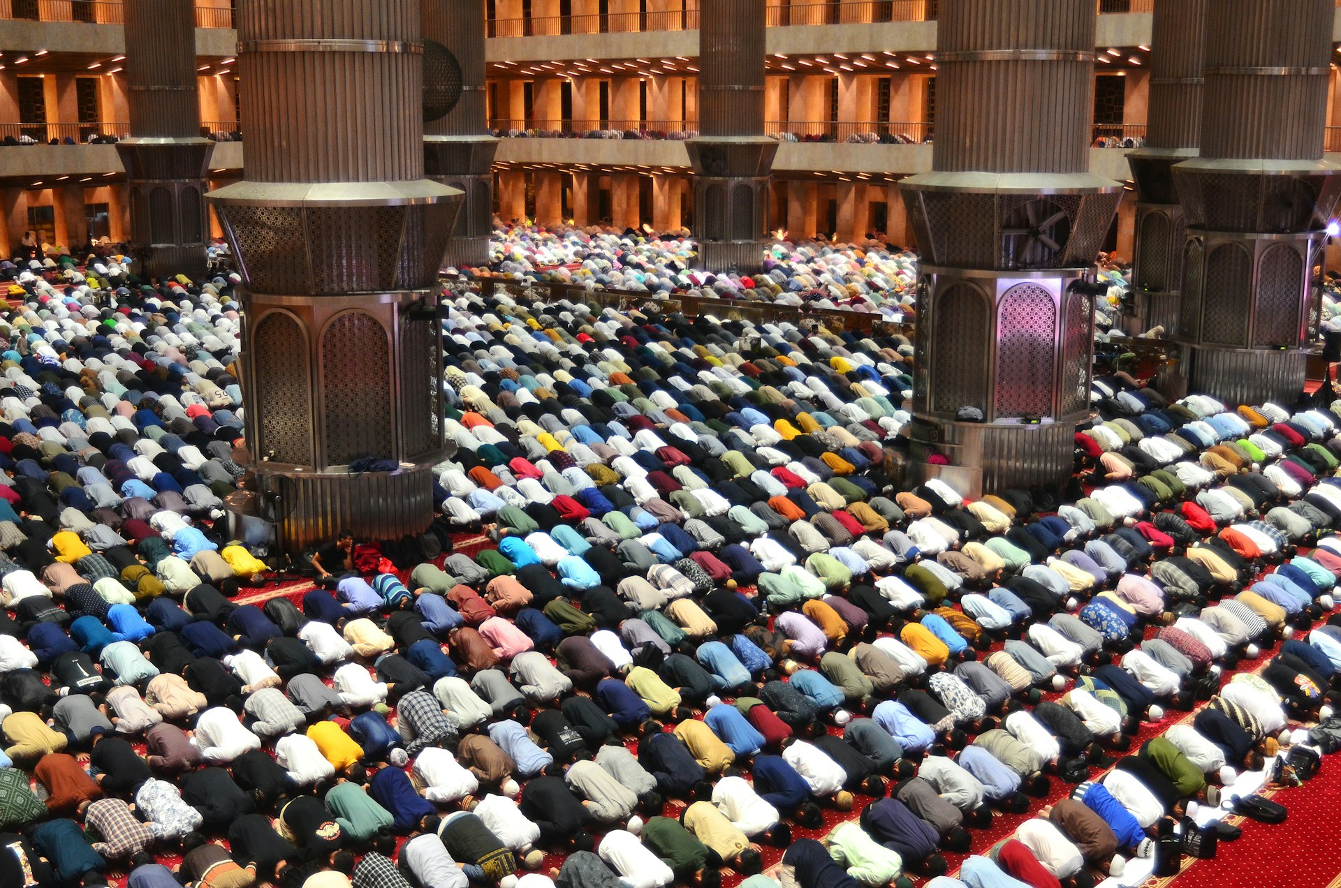 Worshippers pray together inside a grand mosque.